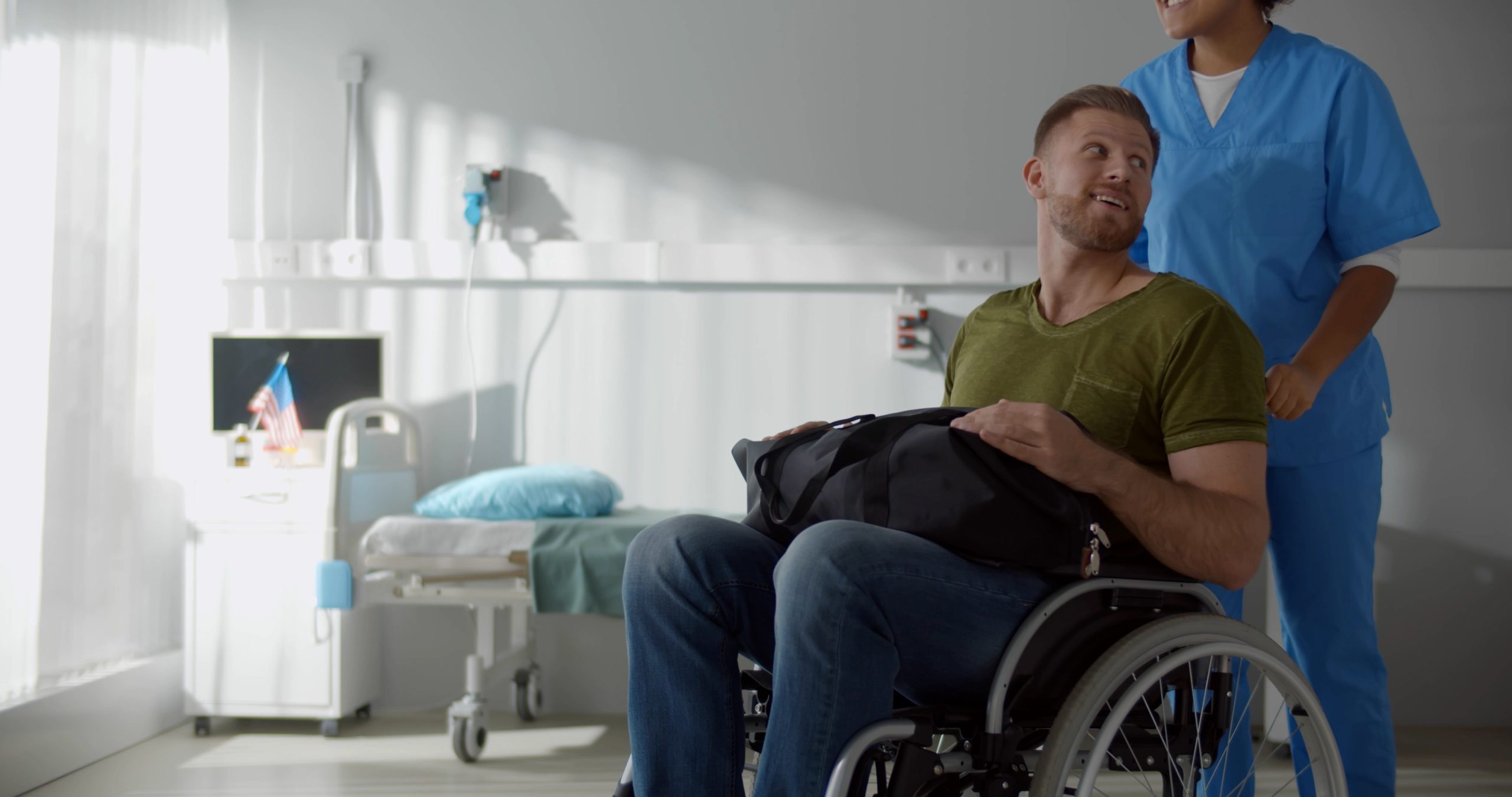 Afro,Female,Nurse,Talking,To,Discharged,Male,Patient,In,Wheelchair