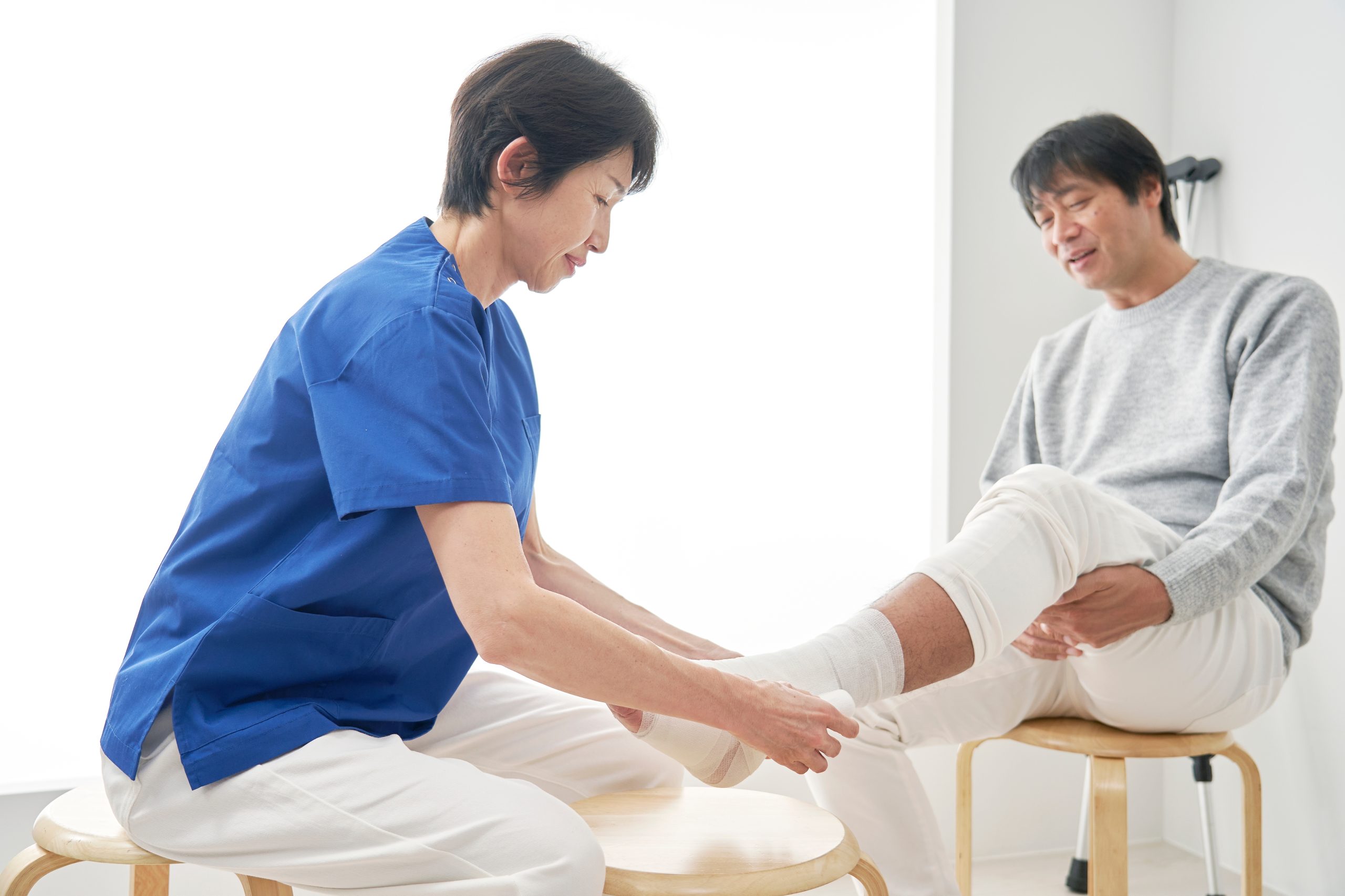 Asian,Nurse,Bandaging,A,Patient's,Ankle