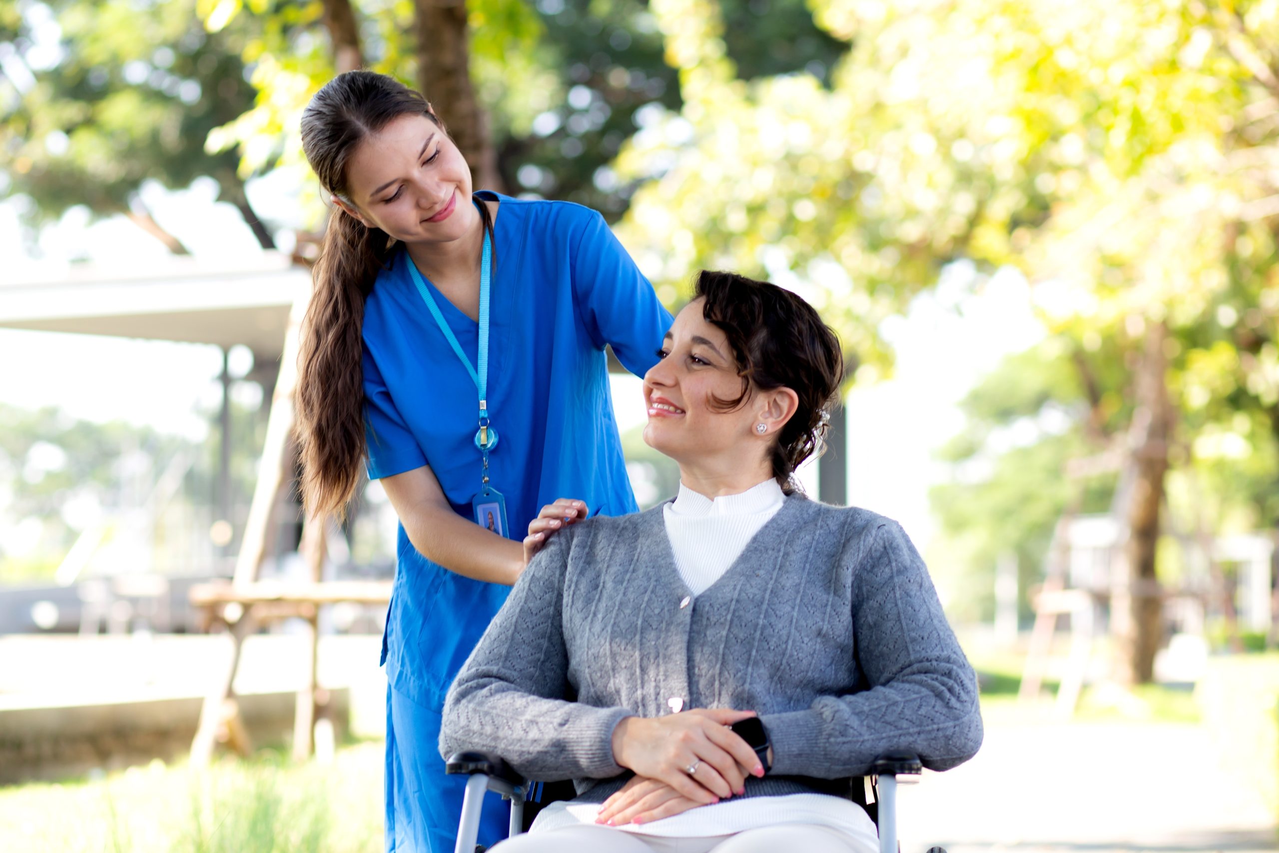 Young,Caucasian,Nurse,Care,With,Patient,While,Pushing,Wheelchair,For